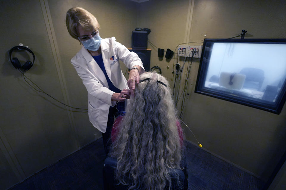 Andrea Gohmert, right, director of the hearing clinic at the University of Texas at Dallas’ Callier Center for Communication Disorders, prepares Lynne Perler for a hearing test during a demonstration at the Callier Center for Communication Disorders Friday, Oct. 23, 2020, in Dallas. As masks have become more wide spread in use during the pandemic, some hearing challenged people have found it difficult to hear mask muffled speakers and have lost the opportunity to read lips to help in communication. (AP Photo/LM Otero)