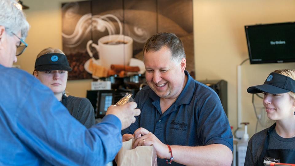 Ross Gelman, a Manhattan Bagel franchiser, helps a customer at his Southampton store.
