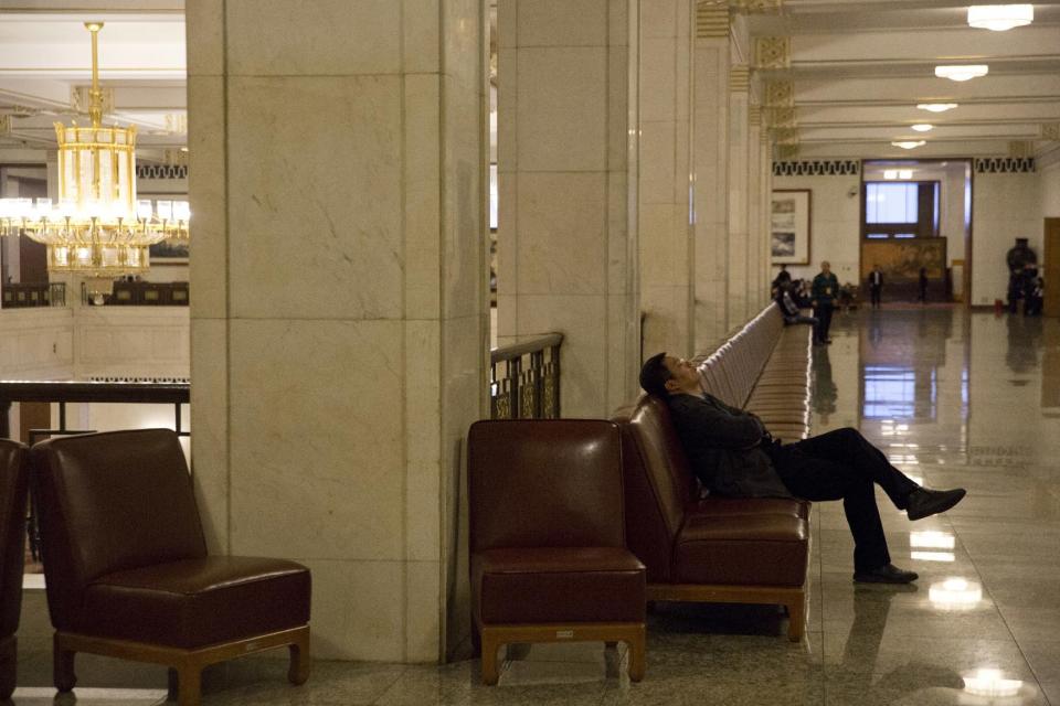 CHANGING SLUG - In this Friday, March 10, 2017 photo, a man naps in the corridor of the Great Hall of the People during a plenary session of the Chinese People's Political Consultative Conference in Beijing. Encompassing the area of 24 football fields, the Great Hall of the People where China’s ceremonial legislature and its official advisory body hold their annual sessions is a cavernous edifice that dwarfs the humans who work in it. (AP Photo/Ng Han Guan)