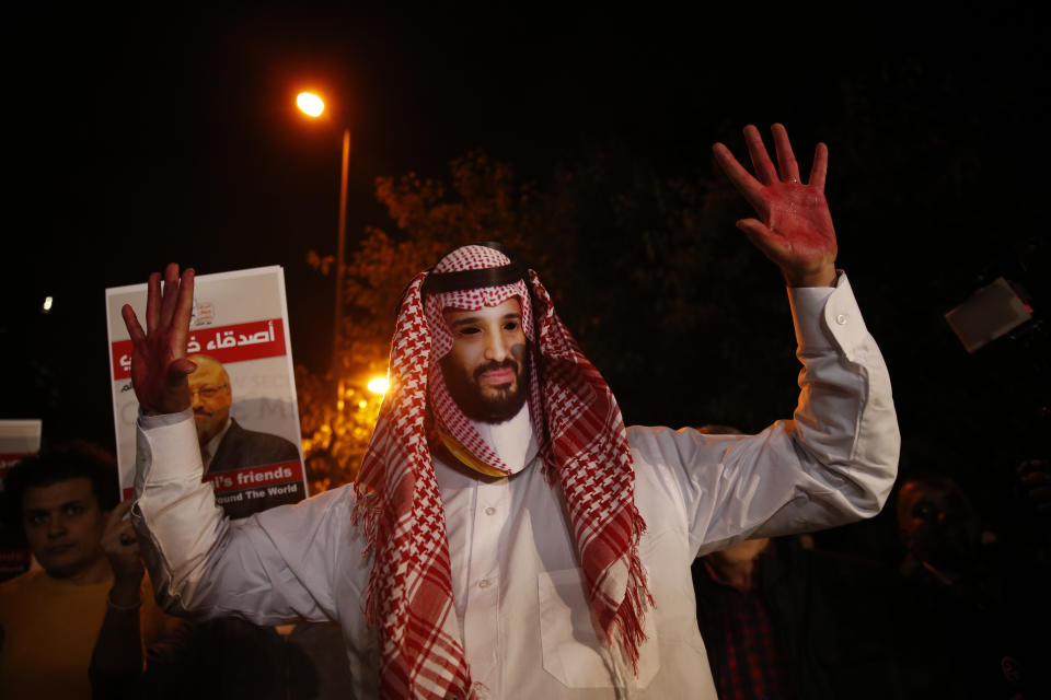 An activist wearing a mask depicting Saudi Crown Prince Mohammed bin Salman, holds up his hands painted with fake blood during a candlelight vigil for Saudi journalist Jamal Khashoggi outside Saudi Arabia's consulate in Istanbul, Thursday, Oct. 25, 2018. A group of Arab and international public, political and media figures are establishing a global association called "Khashoggi's Friends Around the World"; "to achieve justice for the freedom martyr".(AP Photo/Lefteris Pitarakis)