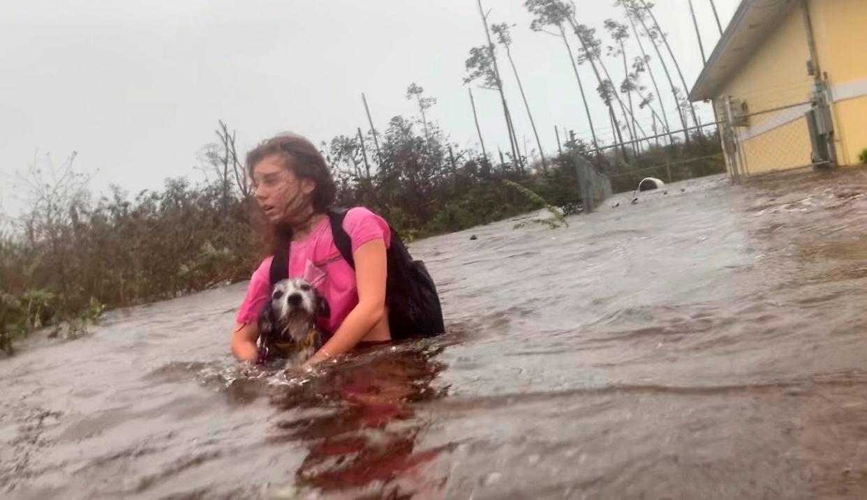 Julia Aylen wades through waist deep water carrying her pet dog as she is rescued from her flooded home during Hurricane Dorian in Freeport, Bahamas on Sept. 3, 2019.