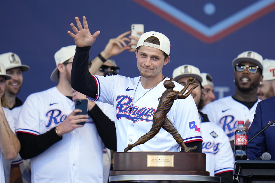 Texas Rangers' Corey Seager waves to fans as he stands behind his MVP trophy during a World Series baseball championship celebration, Friday, Nov. 3, 2023, in Arlington, Texas. The parade comes two days after the Rangers wrapped up the World Series with a 5-0 win on the road against the Arizona Diamondbacks.(AP Photo/Julio Cortez)