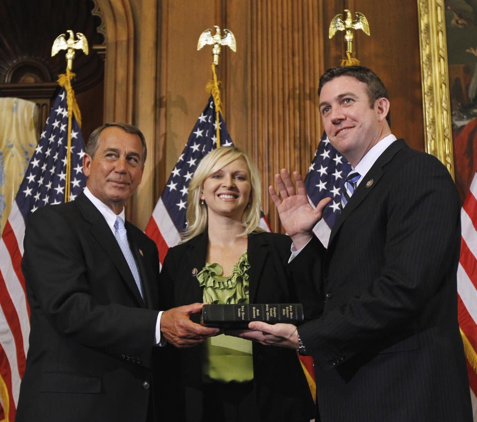 FILE - In this Jan. 5, 2011, file photo, House Speaker John Boehner of Ohio, left, administers the House oath to Rep. Duncan Hunter, R-Calif., as his wife, Margaret, looks on during a mock swearing-in ceremony on Capitol Hill in Washington. Hunter and his wife Margaret faced arraignment Thursday, Aug. 23, 2018, in San Diego on charges they illegally used his campaign account for personal expenses. (AP Photo/Alex Brandon, File)