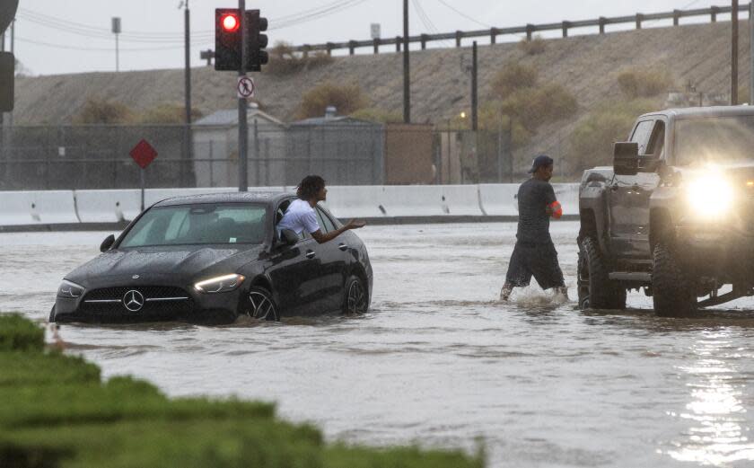 COACHELLA, CA - AUGUST 20, 2023: A driver whose car stalled out on flooded Avenue 48 asks for help from a passerby during tropical storm Hilary on August 20, 2023 in Coachella, California. (Gina Ferazzi / Los Angeles Times)