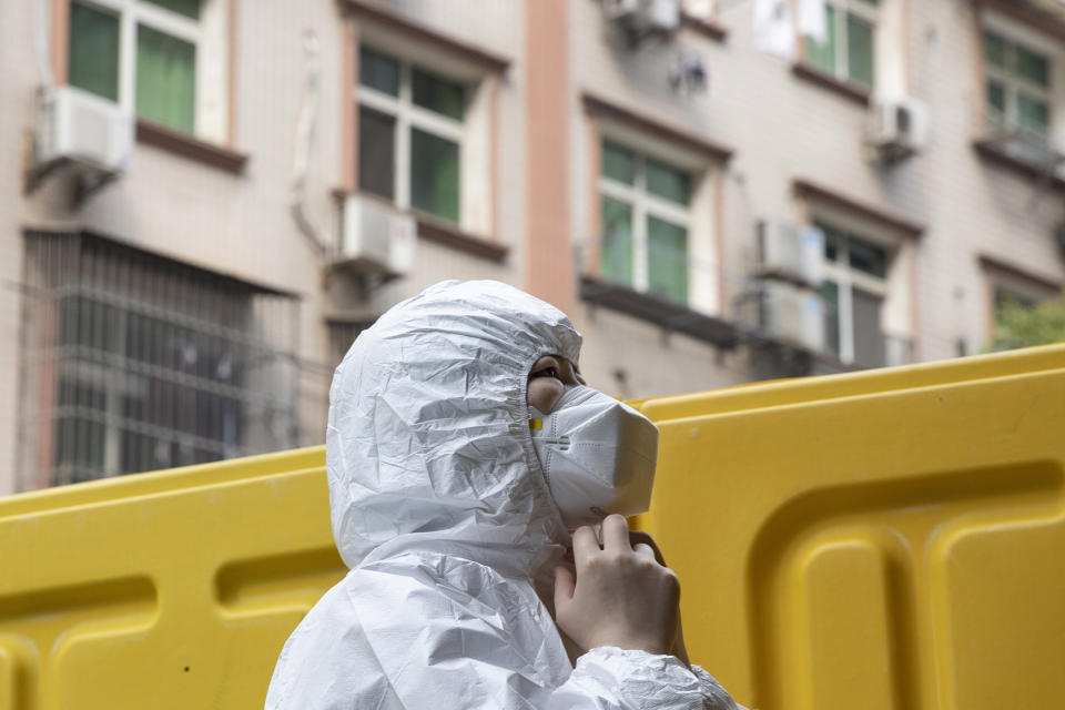 A health worker prepares to take off her protective clothing after administering tests for the coronavirus in Wuhan in central China's Hubei province on Friday, April 3, 2020. Sidewalk vendors wearing face masks and gloves sold pork, tomatoes, carrots and other vegetables to shoppers Friday in the Chinese city where the coronavirus pandemic began as workers prepared for a national memorial this weekend for health workers and others who died in the outbreak. (AP Photo/Ng Han Guan)