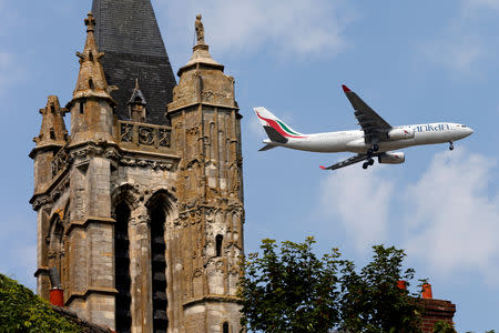 FILE PHOTO: A commercial airliner flies over the 14th century Saint-Pierre-et-Saint-Paul Church, which is classified as an historic monument, in Goussainville-Vieux Pays, 20 kms (12 miles) north of Paris, August 28, 2013. REUTERS/Charles Platiau/File Photo