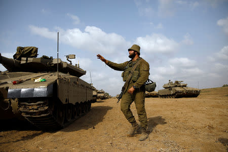An Israeli soldier gestures as military armoured vehicles gather in an open area near Israel's border with the Gaza Strip October 18, 2018. REUTERS/Amir Cohen