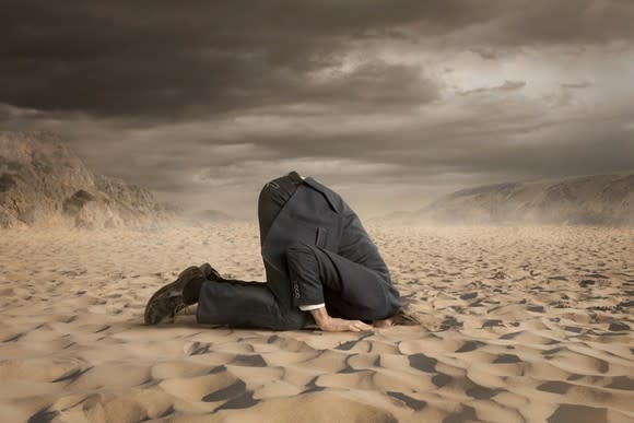 A businessman with his head in the sand.