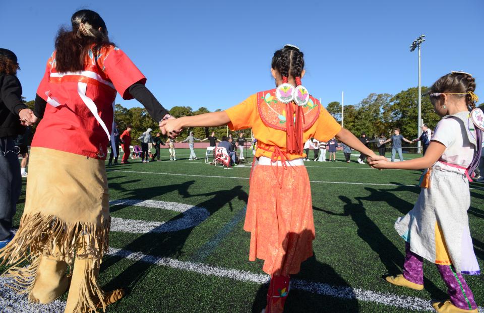 Dancers join hands with Falmouth High School students during an "Indigenous People Dance" on Wednesday at the high school football field.