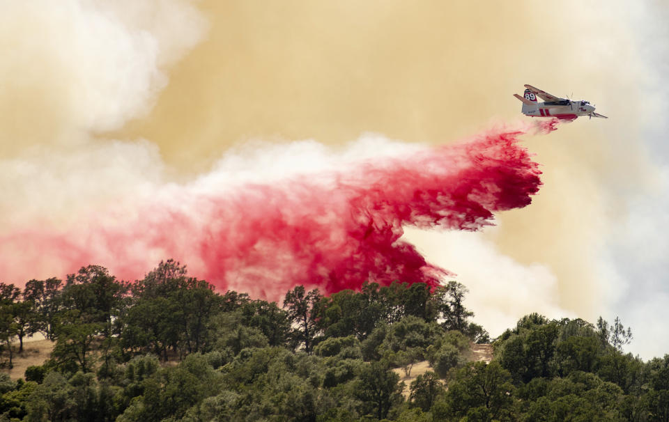 A Cal Fire aircraft drops fire retardant on a hillside in an attempt to box in flames from a wildfire called the Sand Fire in Rumsey, Calif., Sunday, June 9, 2019. (AP Photo/Josh Edelson)