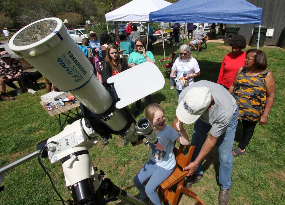 Six-year-old Annabelle Collins gives a thumbs-up to Don Brooks after looking through a telescope at the eclipse as people gathered to watch Monday afternoon, April 8, 2024, at the Gateway Trail in Kings Mountain.