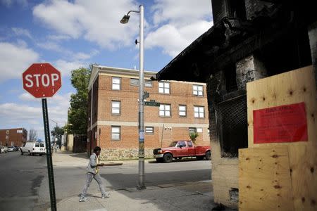 A woman walks by a store damaged from riots after the death of Freddie Gray in Baltimore, Maryland, May 13, 2015. REUTERS/Carlos Barria