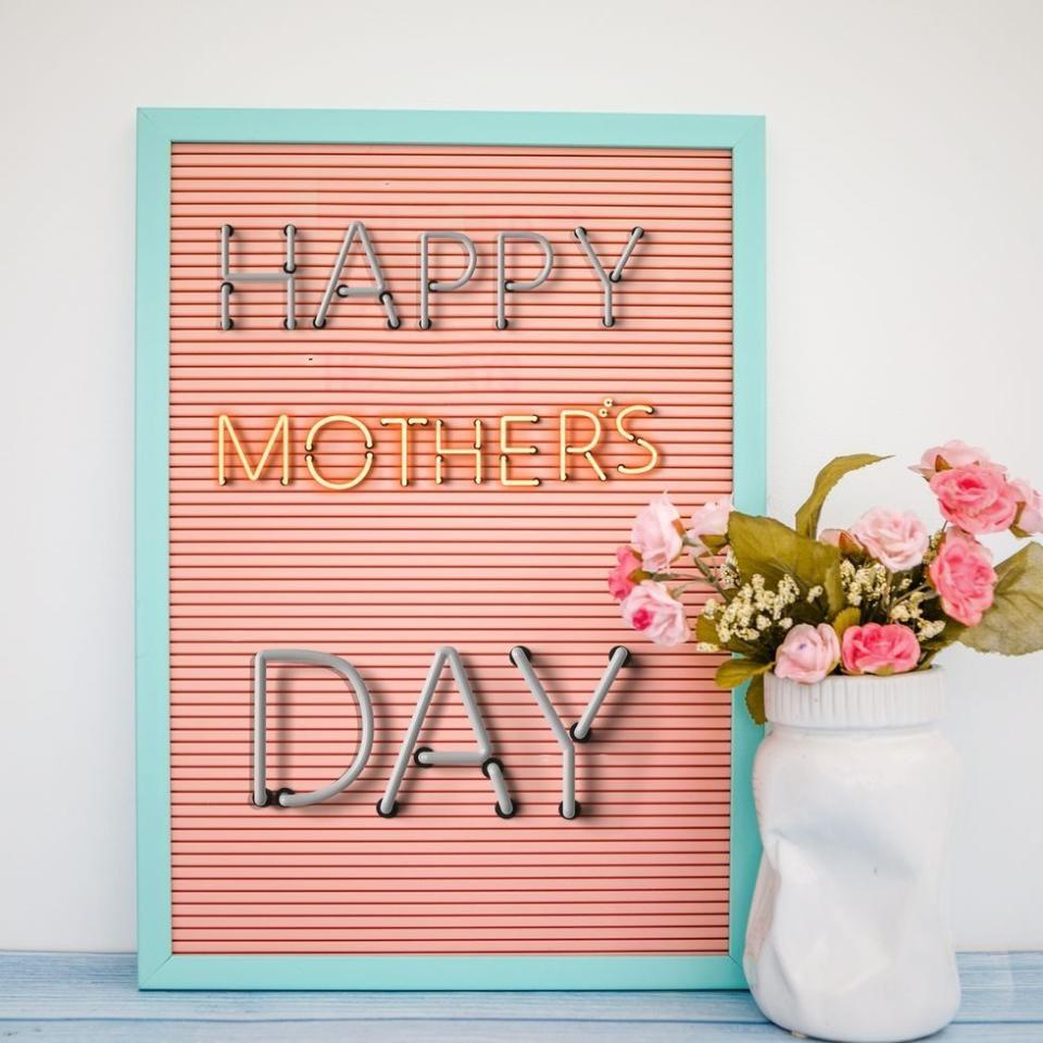 happy mother's day message in lights on small pink marquee with aqua frame, beside pink bouquet in white vase