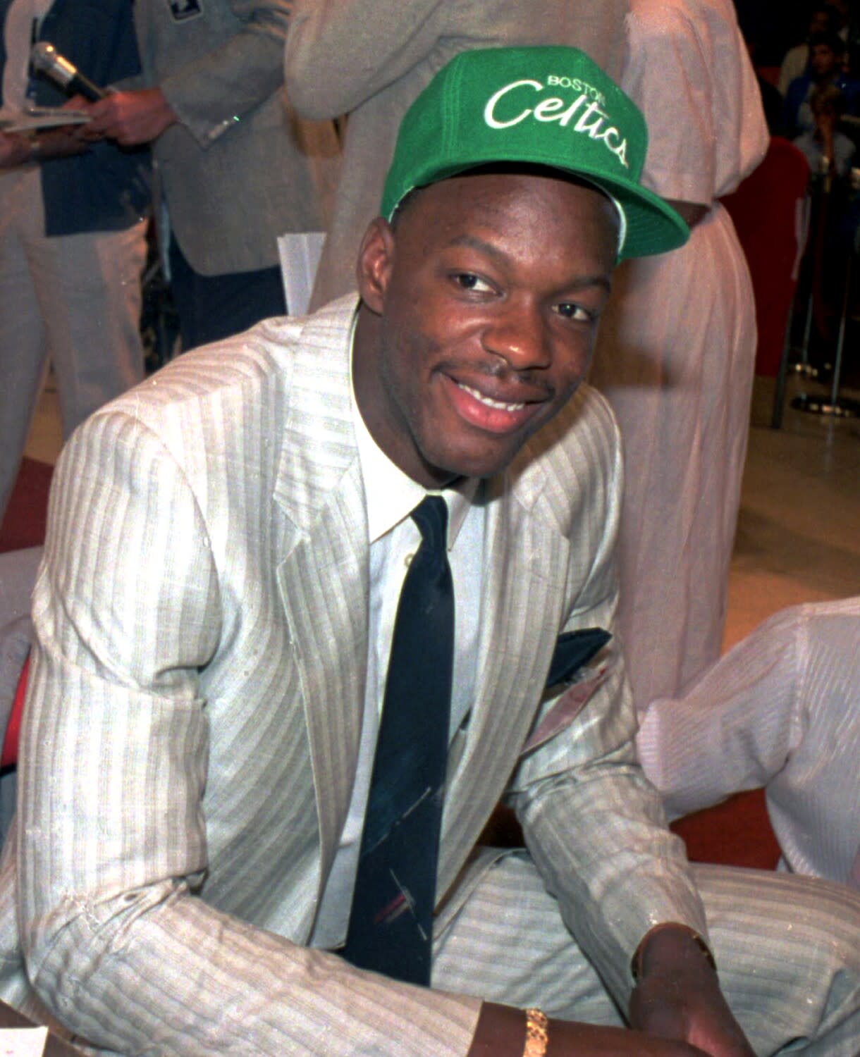 A man in a suit wears a Boston Celtics cap