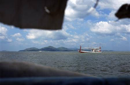 A Thai fishing boat plies the invisible maritime border between Thailand and Myanmar, with the hills of Myanmar visible in the background November 1, 2013. REUTERS/Andrew RC Marshall