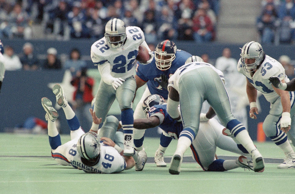 Dallas Cowboys running back Emmitt Smith (22) jumps over teammate Daryl Johnston (48) for a six-yard gain despite the efforts of New York Giants Stacy Dillard (71) and Myron Gyton (29) in the first quarter on Sunday, Nov. 7, 1993 in Irving, Texas. (AP Photo/Ron Heflin)