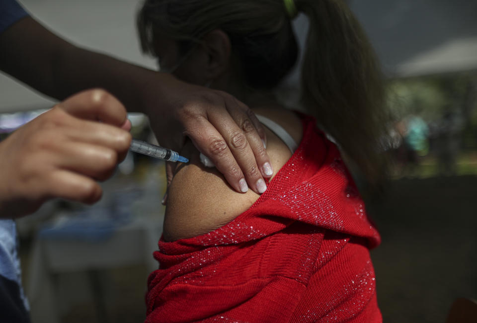 A healthcare worker inoculates a woman with a dose of the Pfizer COVID-19 vaccine at a community center in La Pintana neighborhood of Santiago, Chile, Wednesday, March 31, 2021, during a city-wide lockdown reinstated to help contain the spread of COVID-19. (AP Photo/Esteban Felix)