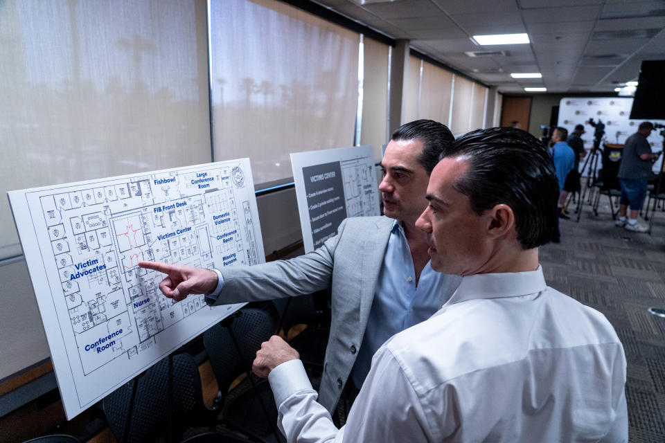 Adam Rack, left, and his brother Anthony Rack, right, of the Rack Law Group, examine renovation layouts before the start of a press conference announcing a renovation project for the Phoenix Police Foundation Victim Center at 2120 N. Central Ave. in Phoenix on Aug. 16, 2022.