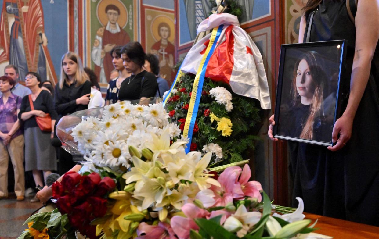 A woman holds a picture of Victoria Amelina, 37, during her funeral service in Mykhaylo Gold Domes in Kyiv (AFP via Getty Images)