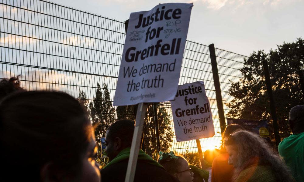 People take part in a silent walk past Grenfell Tower in west London.