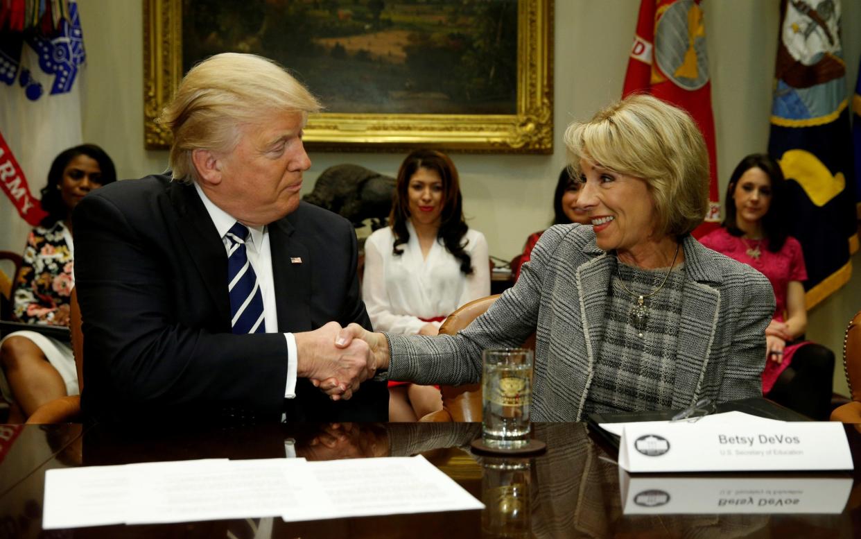 Betsy DeVos, pictured with Donald Trump in 2017, was one of the president's longest-serving officials - Kevin Lamarque/Reuters