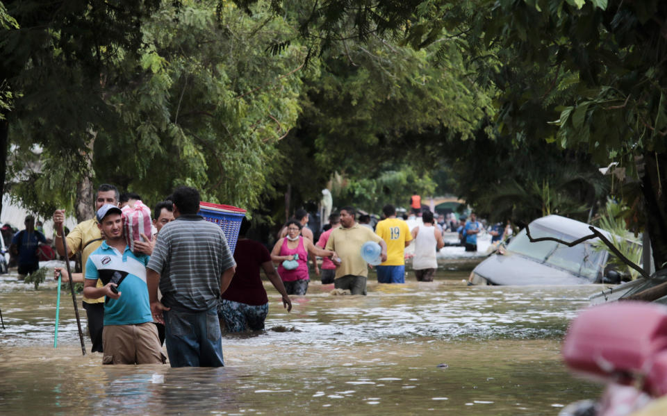 Pobladores caminan junto a vehículos inundados en las calles de Planeta, Honduras, el viernes 6 de noviembre de 2020, luego del paso de la tormenta Eta, que dejó destrucción y muerte en Centroamérica. (AP Foto/Delmer Martínez)