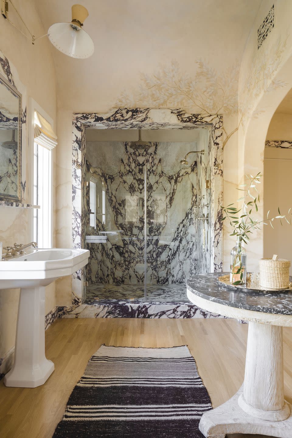 9) A grand bathroom accentuates the home's original architecture, with modern updates including opulent marble finishes.