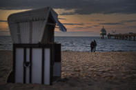 In this Monday May 25, 2020 photo, two tourists stand on the beach on the Baltic island of Usedom near the city of Zinnowitz, Germany. Germany's states, which determine their own coronavirus-related restrictions, have begun loosening lockdown rules to allow domestic tourists to return. (Stefan Sauer/dpa via AP)