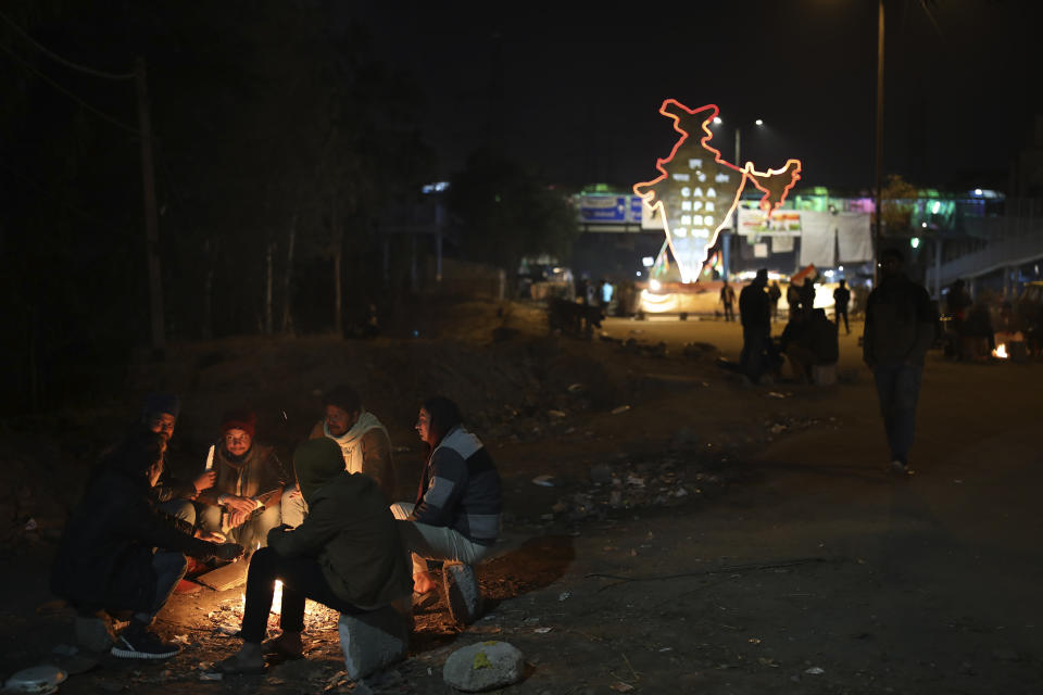 In this early Thursday, Jan. 23, 2020 photo, volunteers keep themselves warm around a bonfire as they man a check-post near the protest site in New Delhi's Shaheen Bagh area, India. Muslim women are transcending the confines of their homes to lay claim to the streets of this nondescript Muslim neighborhood in the Indian capital and slowly transforming it into a nerve center of resistance against a new citizenship law that has unleashed protests across the country. The gathering at Shaheen Bagh started with a handful of women appalled by the violence at a nearby Muslim university during protests against the law on Dec. 15. Since then it has slowly morphed into a nationwide movement, with many women across the country staging their own sit-ins. (AP Photo/Altaf Qadri)