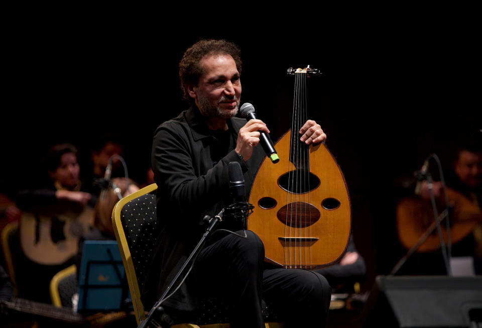 Iraqi virtuoso oud player Naseer Shamma speaks to the audience during a concert at the Iraqi National Theater in Baghdad, Iraq, Friday, Jan. 21, 2022. War kept him away from his beloved homeland for decades. Now Shamma has returned to Iraq with a series of concerts and projects he hopes will support education, culture and the arts in the conflict-scarred nation. (AP Photo/Hadi Mizban)