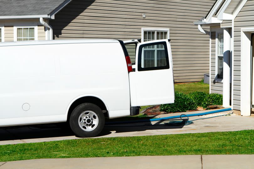 Generic professional carpet & upholstery cleaning service van with hoses coming out the back of the vehicle. Typical American residential subdivision background.