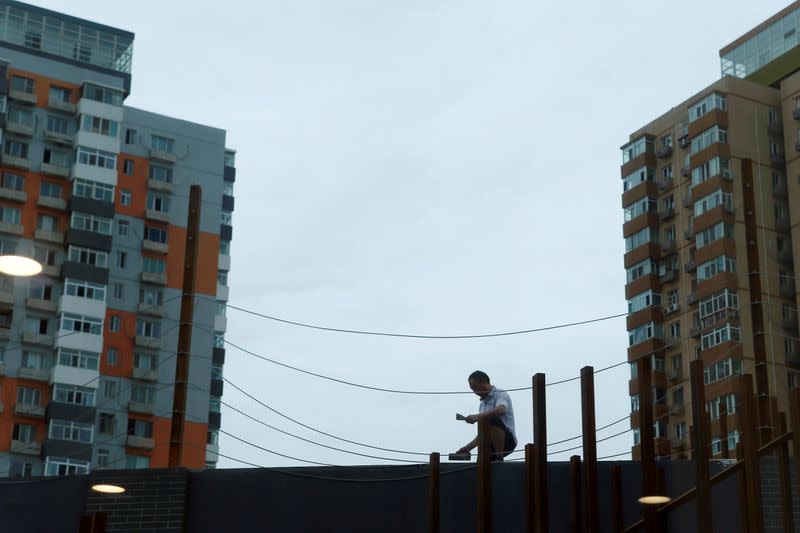 FILE PHOTO: Man works on renovating an office building near residential buildings in Beijing