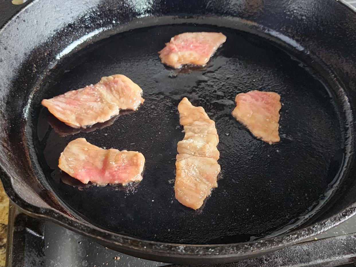 pieces of wagyu steak cooking in a cast-iron skillet