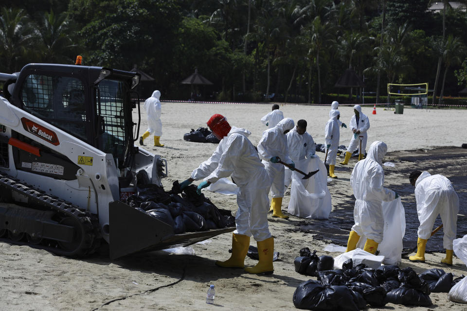 Workers clean oil spill along Sentosa's Tanjong Beach area in Singapore, Sunday, June 16, 2024. (AP Photo/Suhaimi Abdullah)