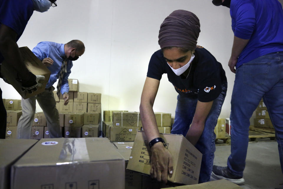 From left, Tim Williams, warehouse assistant for Medisys, Ray Fredericks, assistant director for Medisys, Dr. Abhu Kaur with Khalsa Aid USA, a global humanitarian organization, and Michael Stack, healthcare account representative for Grainger, load dozens of electrical transformers onto a pallet, which will be shipped to New Delhi with oxygen concentrators this week on New York’s Long Island, Friday, May 7, 2021. With teams deployed in India to help support COVID-19 patients, Khalsa Aid USA plans to provide a total of 500 oxygen concentrators and 500 transformers to cities throughout the country. (AP Photo/Jessie Wardarski)