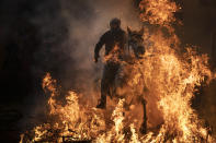 <p>A man rides a horse through a bonfire as part of a ritual in honor of Saint Anthony the Abbot, the patron saint of domestic animals, in San Bartolome de Pinares, Spain, Wednesday, Jan. 16, 2019. On the eve of Saint Anthony’s Day, dozens ride their horses through the narrow cobblestone streets of the small village of San Bartolome during the “Luminarias,” a tradition that dates back 500 years and is meant to purify the animals with the smoke of the bonfires and protect them for the year to come. (AP Photo/Felipe Dana) </p>