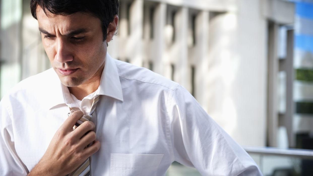 hispanic businessman loosening necktie in office