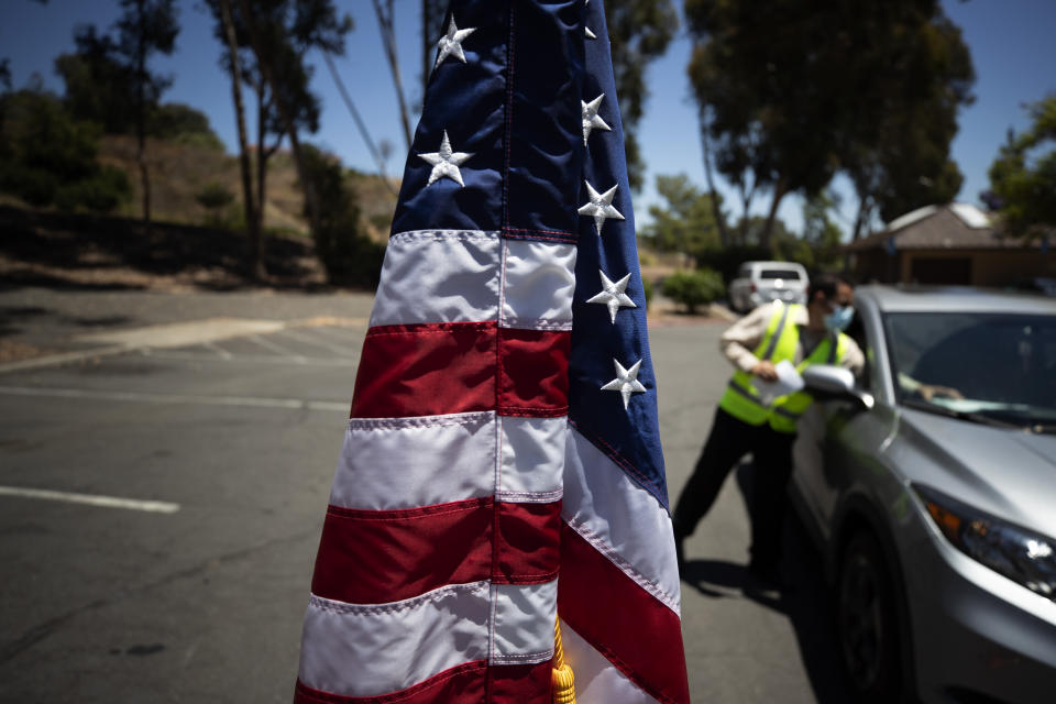 In this June 26, 2020 photo, Immigration Service Officer Bay checks paperwork during a drive-in citizenship ceremony in El Cajon, Calif. The path to becoming a U.S. citizen, and a new voter, had already become longer under President Donald Trump when COVID-19 brought it virtually to a halt. Smaller naturalization ceremonies have resumed -- under socially distant rules that turn a once-joyous and patriotic occasion into something more like a visit to a fast-food restaurant -- but could soon stall again as the nation's citizenship agency faces an unprecedented budget shortfall and the possibility of a furlough for nearly three-fourths of its workforce. (AP Photo/Gregory Bull)