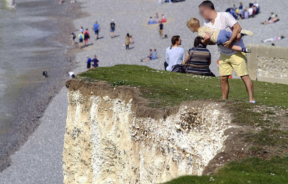 A father clutches his toddler close to the edge of the Seven Sisters cliffs in East Sussex, England. 