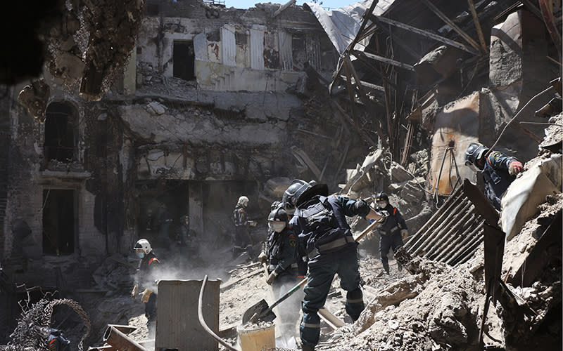 Emergency personnel clear rubble at site of damaged Mariupol theater during the day