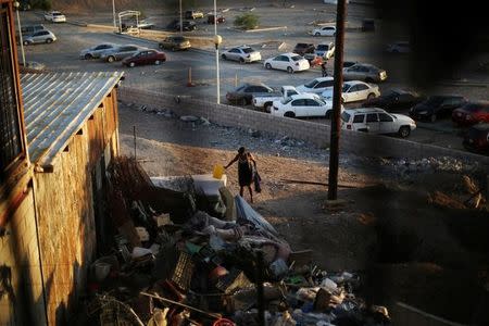 A Haitian migrant walks near garbage at the Hotel del Migrante shelter after leaving Brazil, where she relocated to after Haiti's 2010 earthquake, in Mexicali, Mexico, October 5, 2016. REUTERS/Edgard Garrido