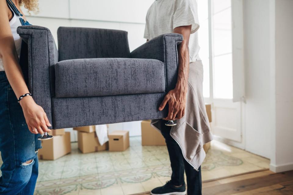 Couple carrying armchair while standing at new house