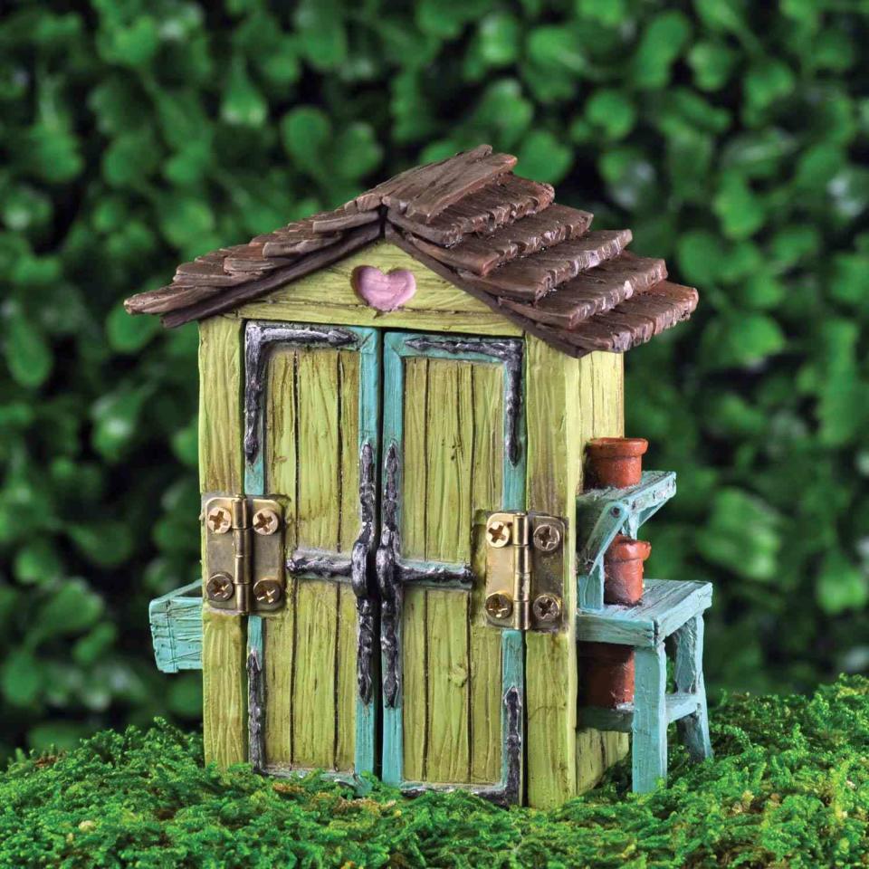 Miniature green garden shed with a blue potting bench, brown roof, and hinges that open the doors