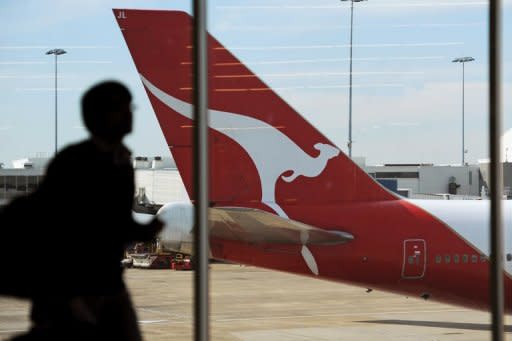 An airport passenger walks past a Qantas plane at Sydney International Airport. Qantas Airways on Wednesday severed a lucrative marketing deal with Tourism Australia after claiming its boss was leading a consortium trying to unseat the airline's management and buy out the company