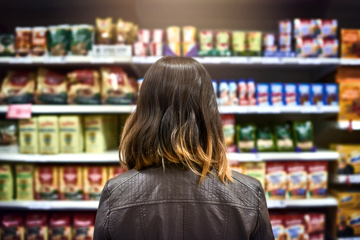A woman looks at what to buy at the grocery store .