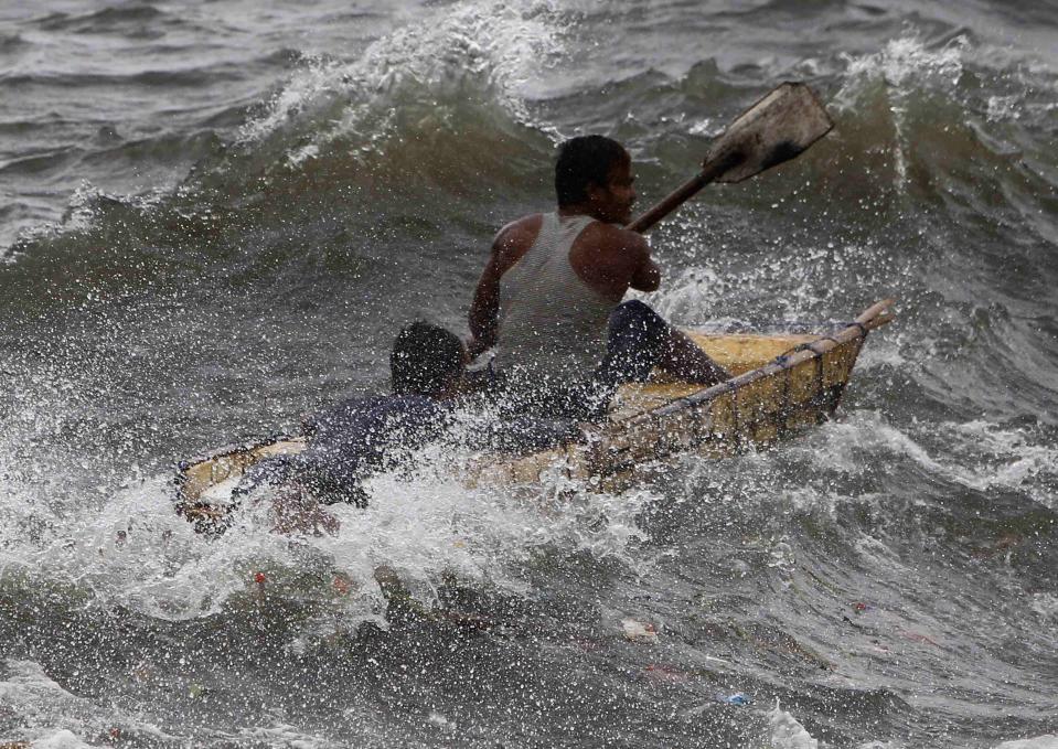 A man and a boy paddle through rough waves brought by Typhoon Usagi in Manila