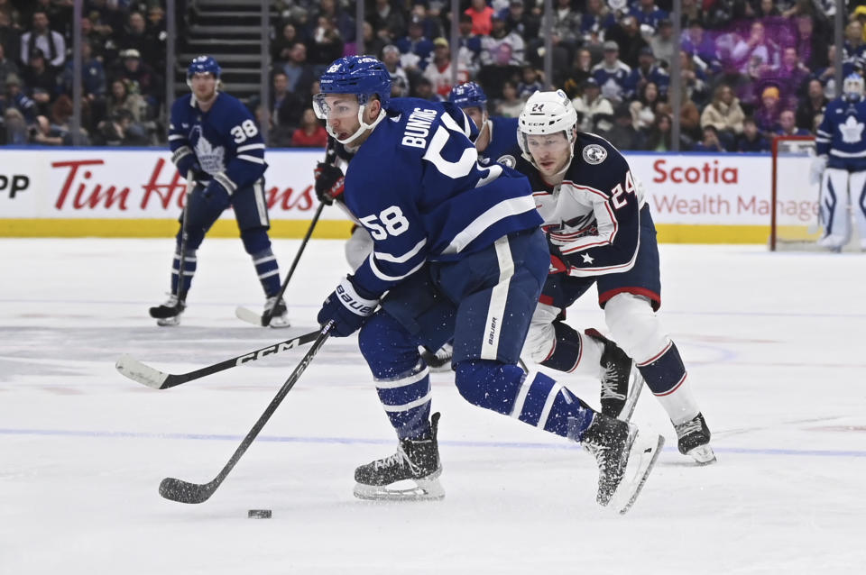 Toronto Maple Leafs left winger Michael Bunting (58) crosses into the offensive zone ahead of Columbus Blue Jackets right winger Mathieu Olivier (24) during second-period NHL hockey game action Saturday, Feb. 11, 2023, in Toronto. (Jon Blacker/The Canadian Press via AP)