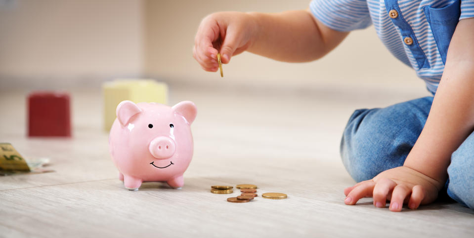 A child putting a coin into a piggybank.