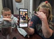 Darra Ann Morales, right, shows a photo of her son Chaz Morales and his family on her phone, as Chaz Jr., 10, comforts his grandmother at their home in Slidell, La., Wednesday, April 14, 2021. Darra Ann Morales is the mother and Chaz Jr. is the son of Chaz Morales, who is one of the crew members missing from the capsized vessel Seacor Power that departed from Port Fourchon when severe weather struck Tuesday. (Max Becherer/The Times-Picayune/The New Orleans Advocate via AP)