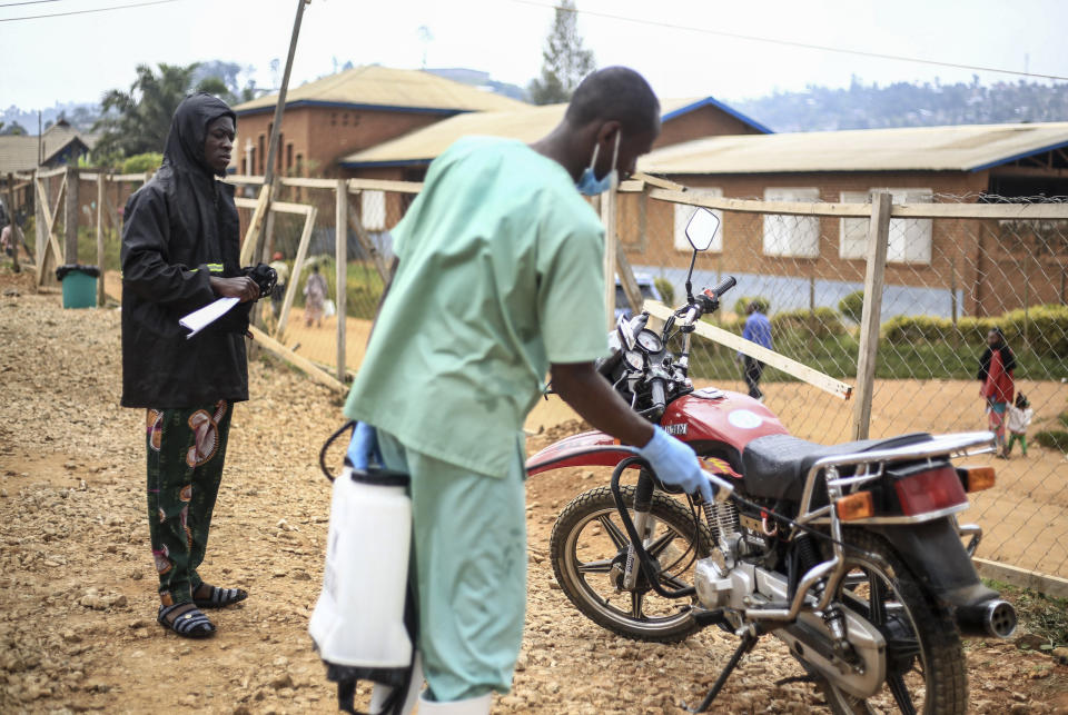 Health workers decontaminate the motorbike of Germain Kalubenge, left, upon his arrival after transporting a suspected Ebola case to an Ebola transit center where potential cases are evaluated, in Beni, Congo, Thursday, Aug. 22, 2019. Kalubenge is a rare motorcycle taxi driver who is also an Ebola survivor in eastern Congo, making him a welcome collaborator for health workers who have faced deep community mistrust during the second deadliest Ebola outbreak in history. (AP Photo/Al-hadji Kudra Maliro)